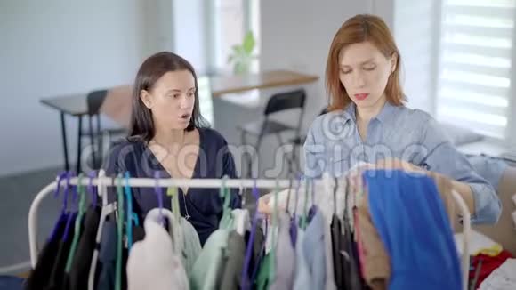 一个女人在房间里把衣服挂在衣架上她的女朋友正在用滑稽的脸切线视频的预览图