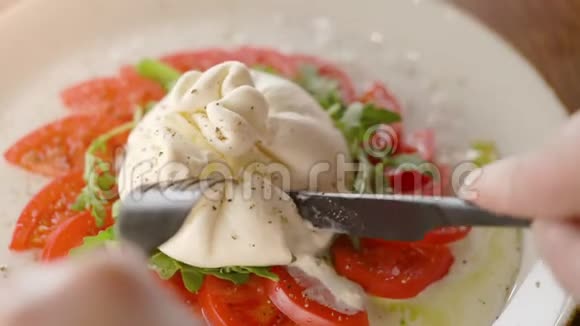 用刀叉切西红柿吃美味的巴拉塔奶酪视频的预览图