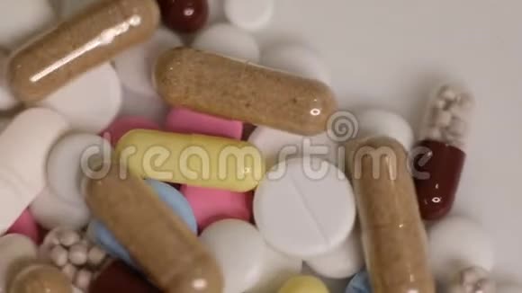 拍摄慢动作视频不同种类的药丸落在白色背景上的慢动作多色平板电脑视频的预览图