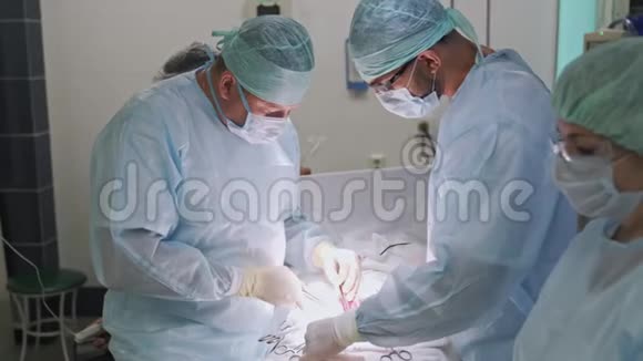 手术期间穿无菌服装的医生和护士团队手术室外科医生侧视视频的预览图