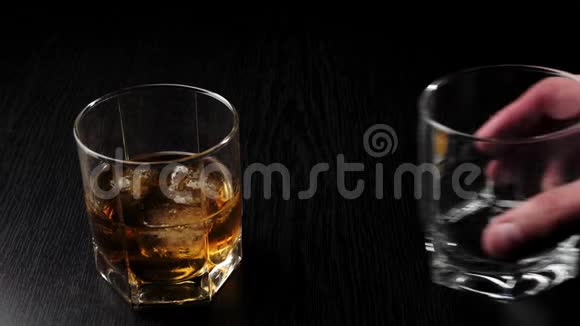 豪华威士忌手把空杯子放在玻璃旁边在黑桌上放着真正冷冰的金色威士忌不倒翁威士忌视频的预览图