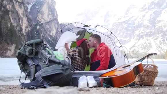 坐在帐篷里的年轻夫妇他们亲吻并关闭帐篷视频的预览图