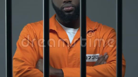 双手交叉的黑人罪犯站在监狱里等待判决视频的预览图