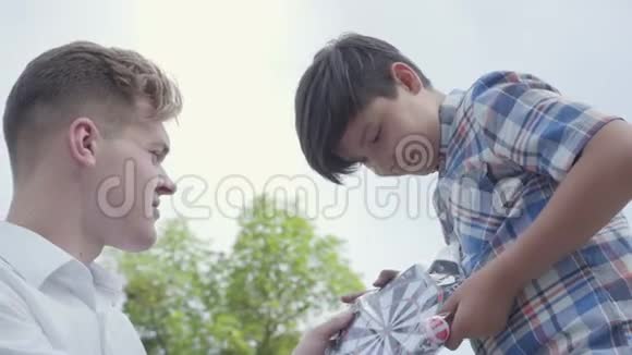 可爱的年轻父亲和他可爱的儿子看着包裹特写中的飞镖可爱的男孩收到了爸爸的礼物视频的预览图