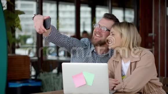 年轻开朗的女士和小伙子正在咖啡馆里用手机拍照视频的预览图