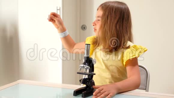 女孩把玻璃幻灯片插入显微镜视频的预览图