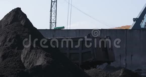 一个大桶把黑色的煤倒在一个大煤堆上视频的预览图