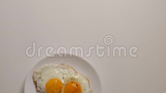 盘子里有两个煎蛋把盘子和煎蛋放在木桌上用煎蛋把白瓷盘合上视频的预览图