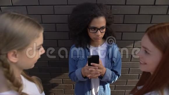 傲慢的女青少年拿着学生智能手机在学校后院欺凌视频的预览图