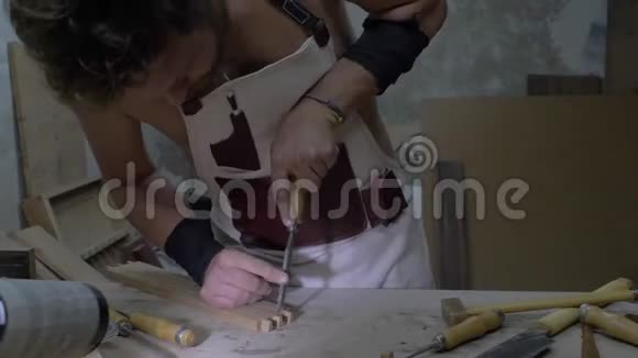木匠用凿子在一个工作台上用一个木部雕刻一个燕尾木工加工木板4k4k录像视频的预览图