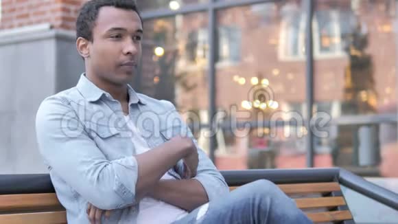 年轻的非洲男人坐在长凳上走开了视频的预览图