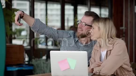 情侣正坐在户外咖啡馆里用智能手机相机自拍视频的预览图