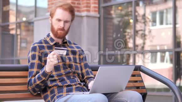 网上购物失败红发胡子年轻人坐在长凳上视频的预览图