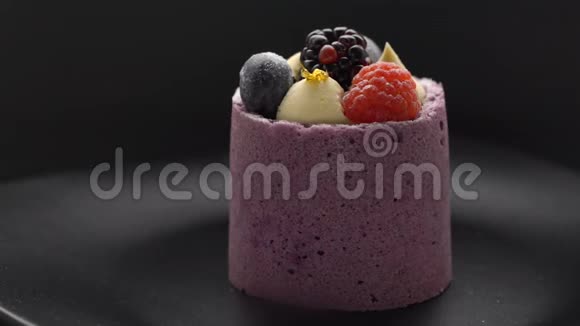 美味的蛋糕配上蓝莓慕斯和新鲜的覆盆子蓝莓在黑盘上旋转视频的预览图