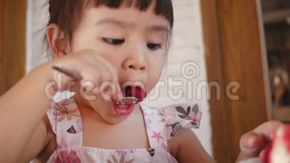 可爱的亚洲小女孩在咖啡馆里吃桑葚蛋糕视频的预览图