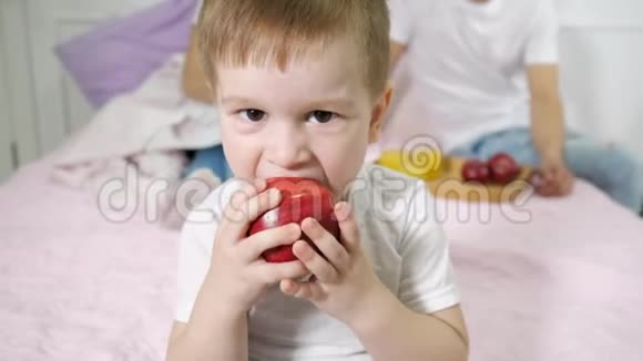 小男孩正在父母卧室里吃苹果他的父母坐在床上视频的预览图