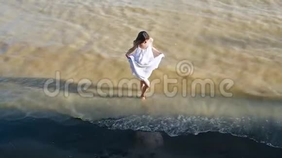 穿裙子的女孩在海滩上跳舞女人笑旋转从上面拍摄视频的预览图