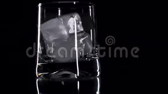 冰块被扔进黑底的威士忌玻璃杯里视频的预览图