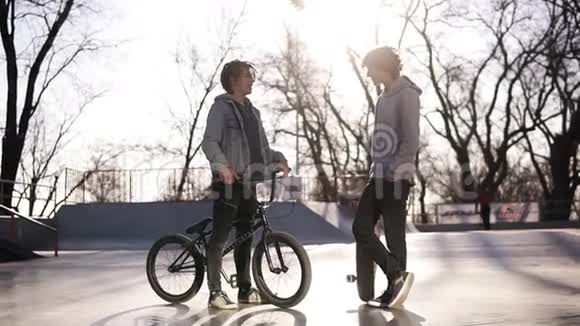 一个滑板手和bmx骑手在户外在城市滑板公园相遇朋友们在溜冰场交流站在里面视频的预览图