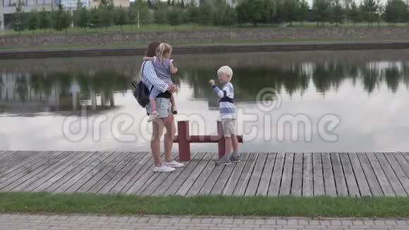 母亲和孩子们在夏天沿着河堤散步视频的预览图