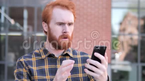 户外红发胡子青年男子在使用智能手机时因失物招领视频的预览图