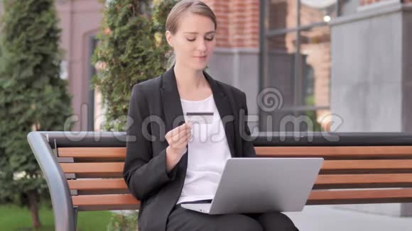 年轻女商人坐在长凳上的网上购物失败视频的预览图