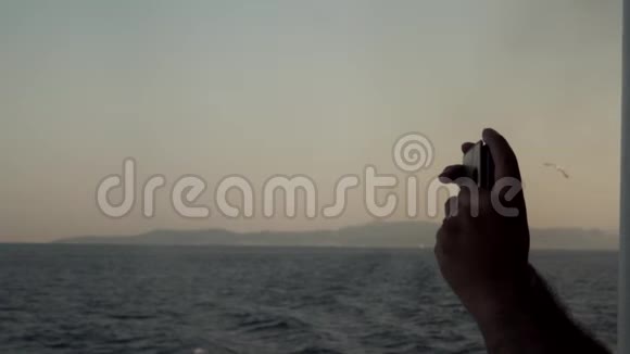 男子用电话拍摄帆船海洋太阳蓝色海洋地平线和海洋的照片旅费视频的预览图