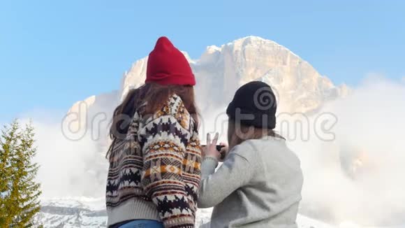 两个年轻女子站在一片阴云密布的群山背景上自拍视频的预览图