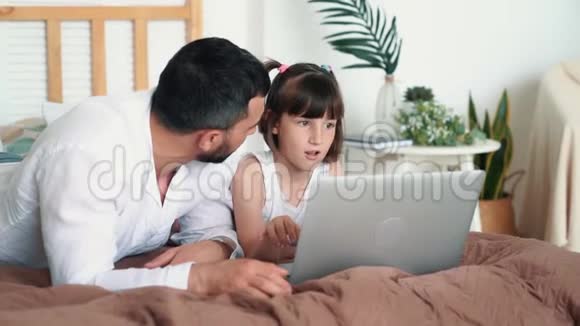 年轻的父亲和他的女儿一起学习笔记本电脑慢动作视频的预览图
