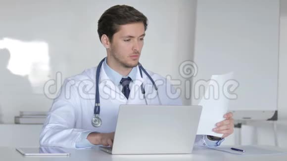 年轻医生在电脑及医疗文件工作视频的预览图