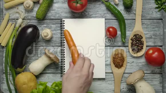 无法辨认的厨师一边吃胡萝卜一边看菜谱视频的预览图