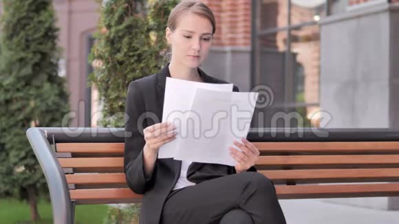 年轻的女商人在户外坐着看文件视频的预览图