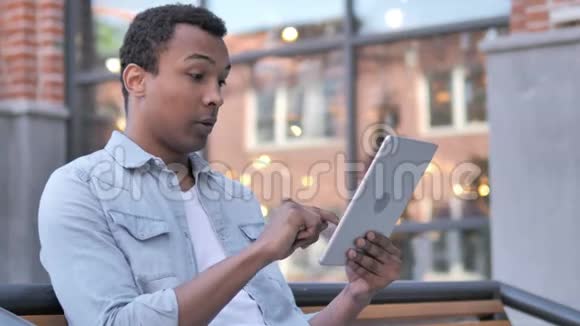 非洲男子户外坐桌视频聊天视频的预览图