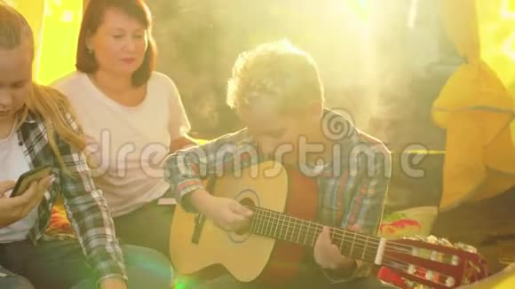 妈妈带着儿子和女儿在帐篷里玩吉他视频的预览图