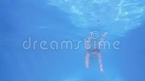 那个穿着一件红色泳衣的女孩在水下游泳女孩游到镜头前水下射击视频的预览图