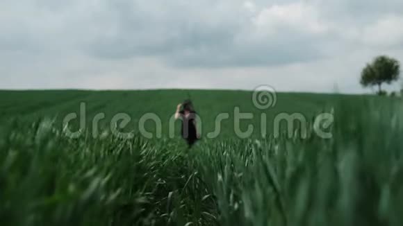 戴着黑帽子的女孩独自站在田野的中央视频的预览图