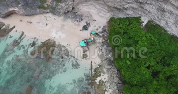在一个热带岛屿的海滩上有一艘坠毁的船在岩石上俯视4k视频的预览图