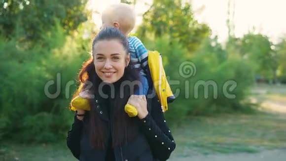 日落时分妈妈带着她的孩子在公园里穿着一件黄色的夹克他们开心地笑着视频的预览图