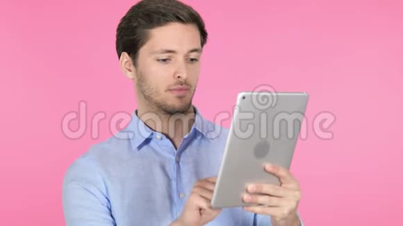 粉红背景下使用平板电脑的年轻人视频的预览图