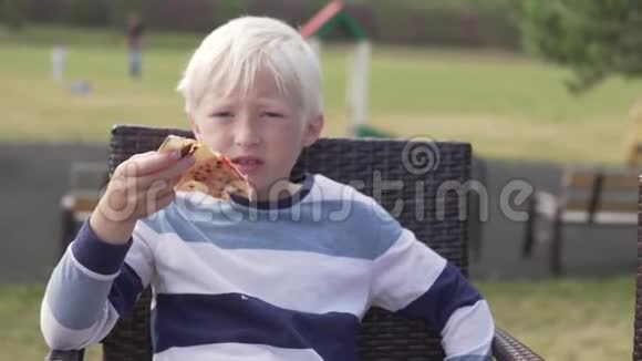 金发男孩在街头餐馆吃披萨视频的预览图