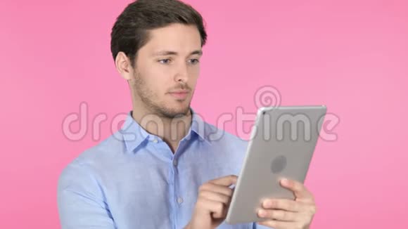 年轻人在平板电脑上庆祝成功粉色背景视频的预览图