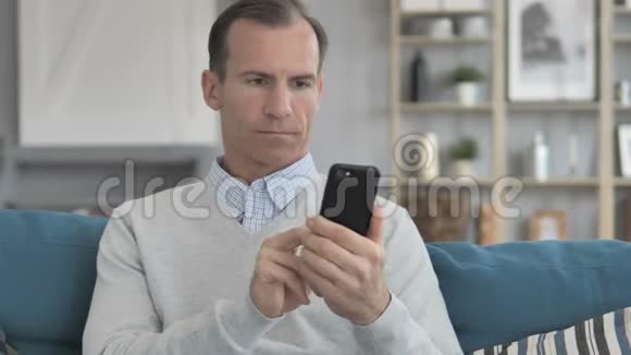 中老年人坐在沙发上用智能手机聊天视频的预览图