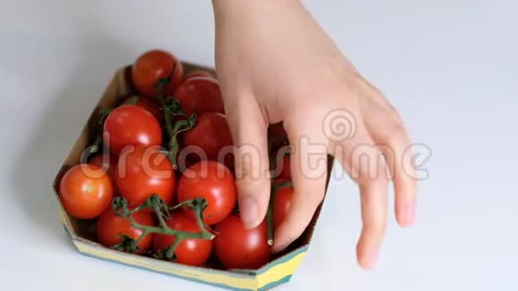 女人用食物胶片在白色桌子上储存食物樱桃番茄一次性塑料包装慢动作视频的预览图
