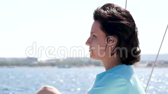 年轻的黑发女人在海上的游艇上女孩摸了摸她的头发头发在风中飘扬游艇上的女孩视频的预览图