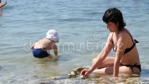 一个孩子和他的妈妈在海边玩石子幸福家庭和家庭度假的概念视频的预览图