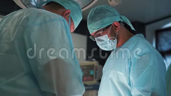 两名医生在手术期间穿着无菌衣服和口罩的肖像慢动作视频的预览图