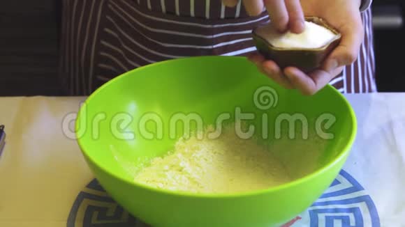 在家庭厨房里的绿色碗里女性手的特写动作缓慢地向面粉中加入盐烹饪煎饼视频的预览图