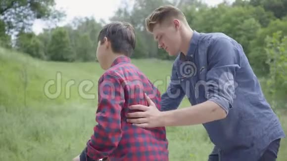 可爱的年轻父亲教他的儿子在公园里骑滑板车他支持孩子帮助他继续视频的预览图