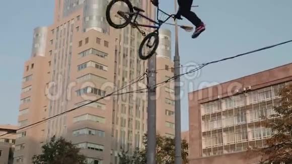自行车跳过BMX自行车上的电线并做背部尾鞭天空和城市建筑背景视频的预览图