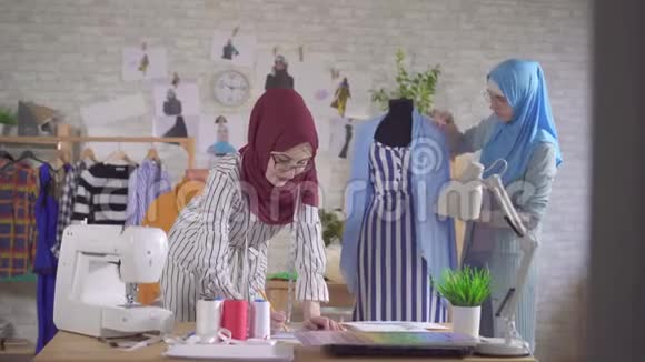 年轻的穆斯林女性时装设计师在现代工作室工作视频的预览图